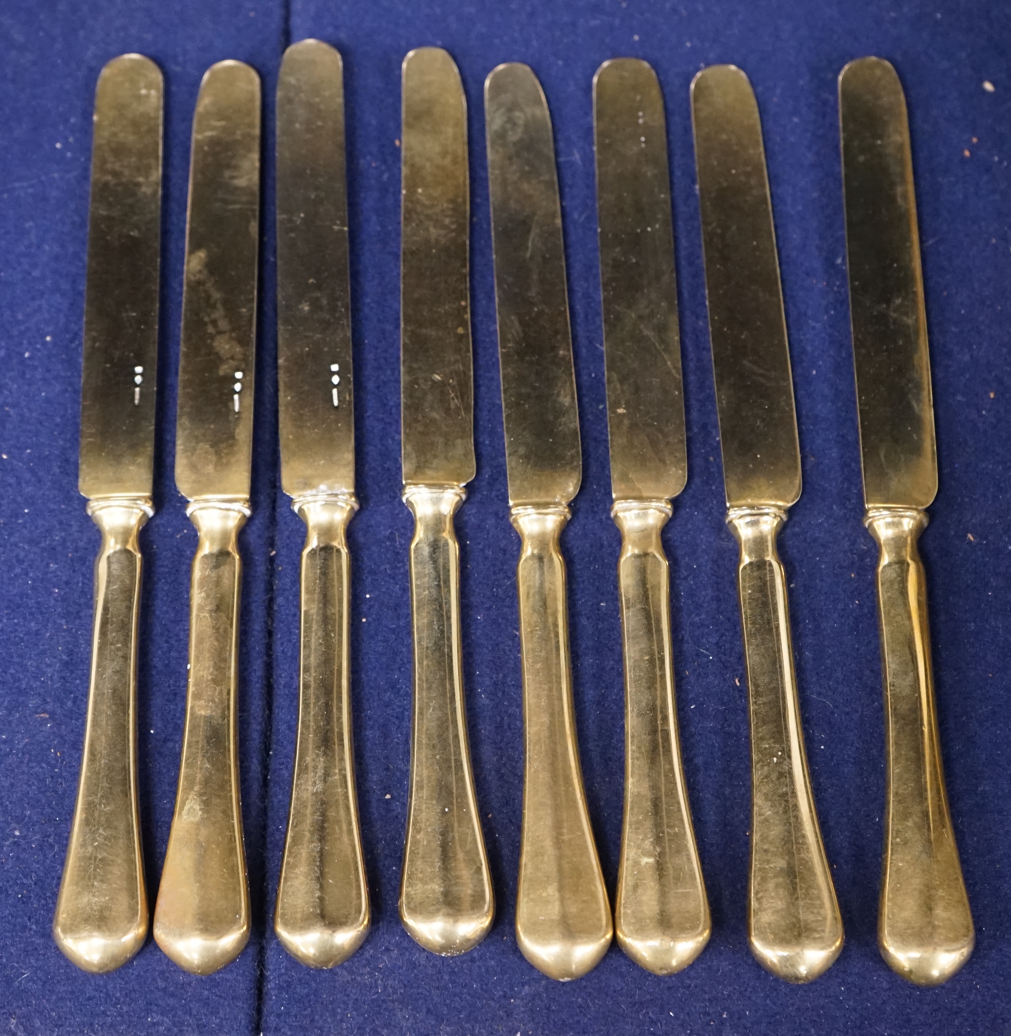 A set of eight French gilt plated dessert knives, 20cm. Condition- fair to good, some nicks and scratches